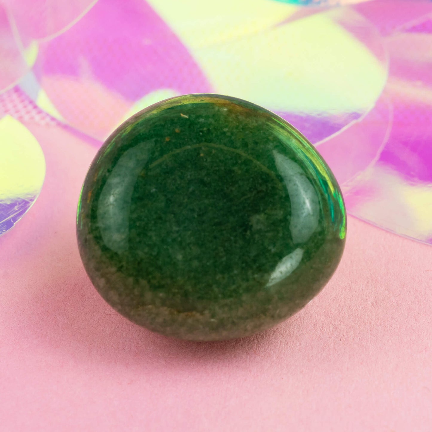 Happiness Enchanters green aventurine crystal on a pink holographic backdrop