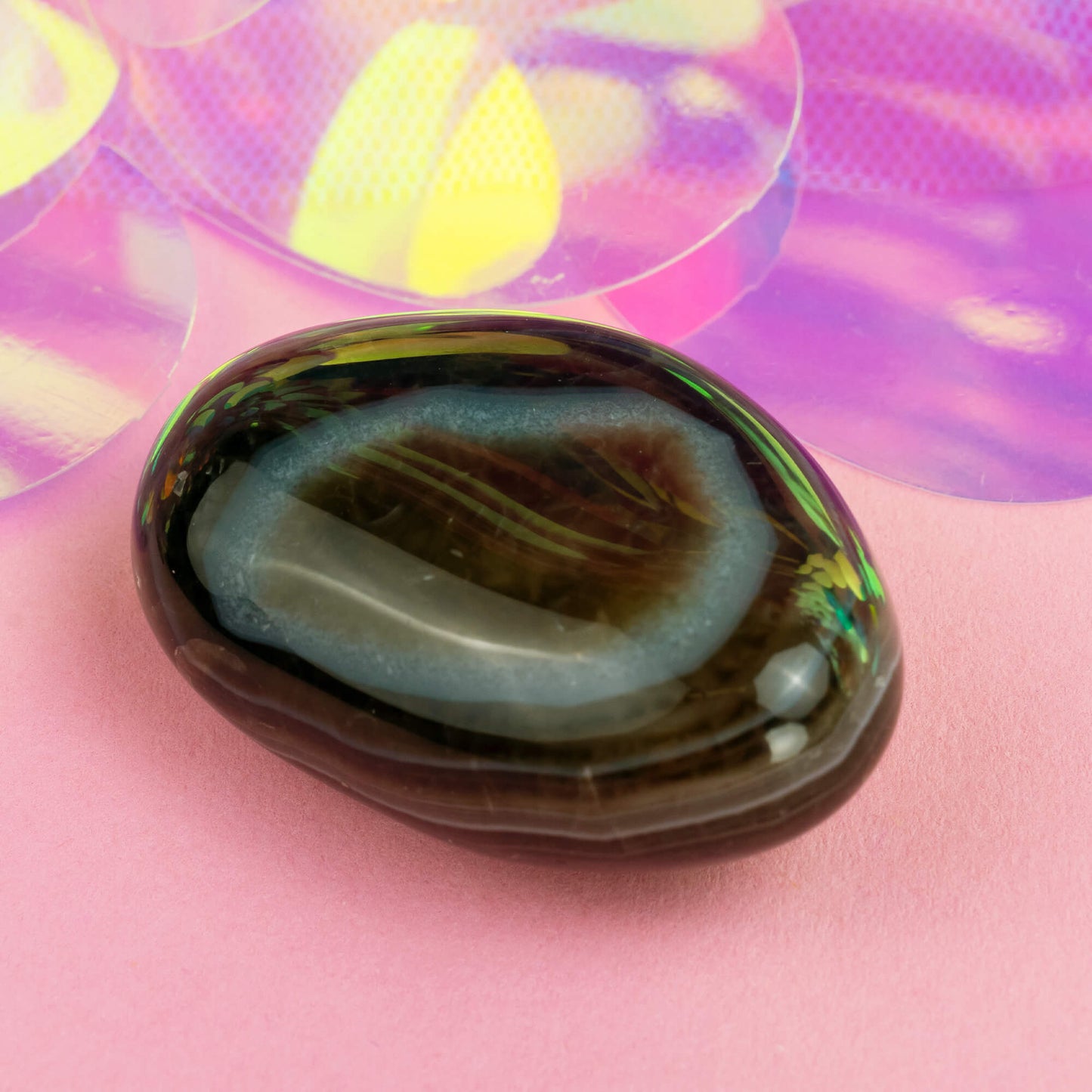 Happiness Enchanters agate crystal on a pink holographic backdrop