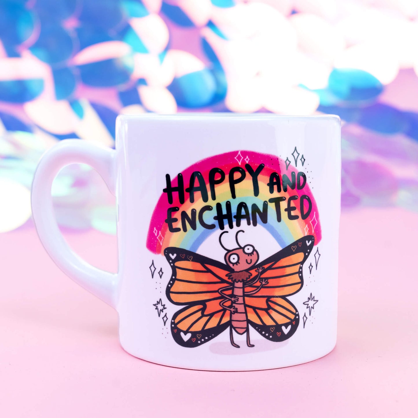 Side view of a white ceramic mug featuring a colourful butterfly character beneath a rainbow, accompanied by the text "Happy and Enchanted." The mug sits against a pastel backdrop, highlighting the enchanting and joyful design created by Happiness Enchanters.