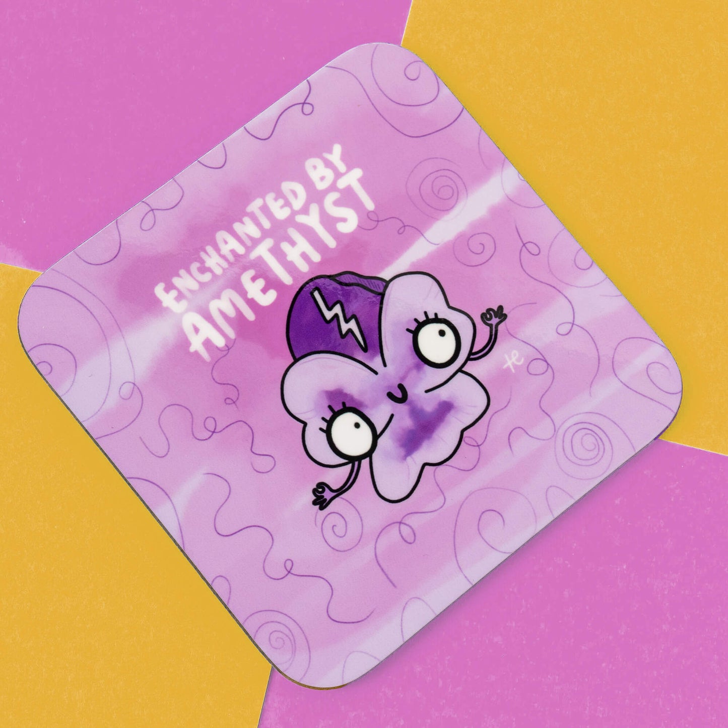 Happiness Enchanters coaster featuring a whimsical illustration of an enchanted amethyst character with wide eyes and a quirky smile, surrounded by a purple and white swirl pattern. The text 'Enchanted by Amethyst' is displayed at the top. The background combines yellow and pink colours. Ideal for adding a touch of magic to any space.