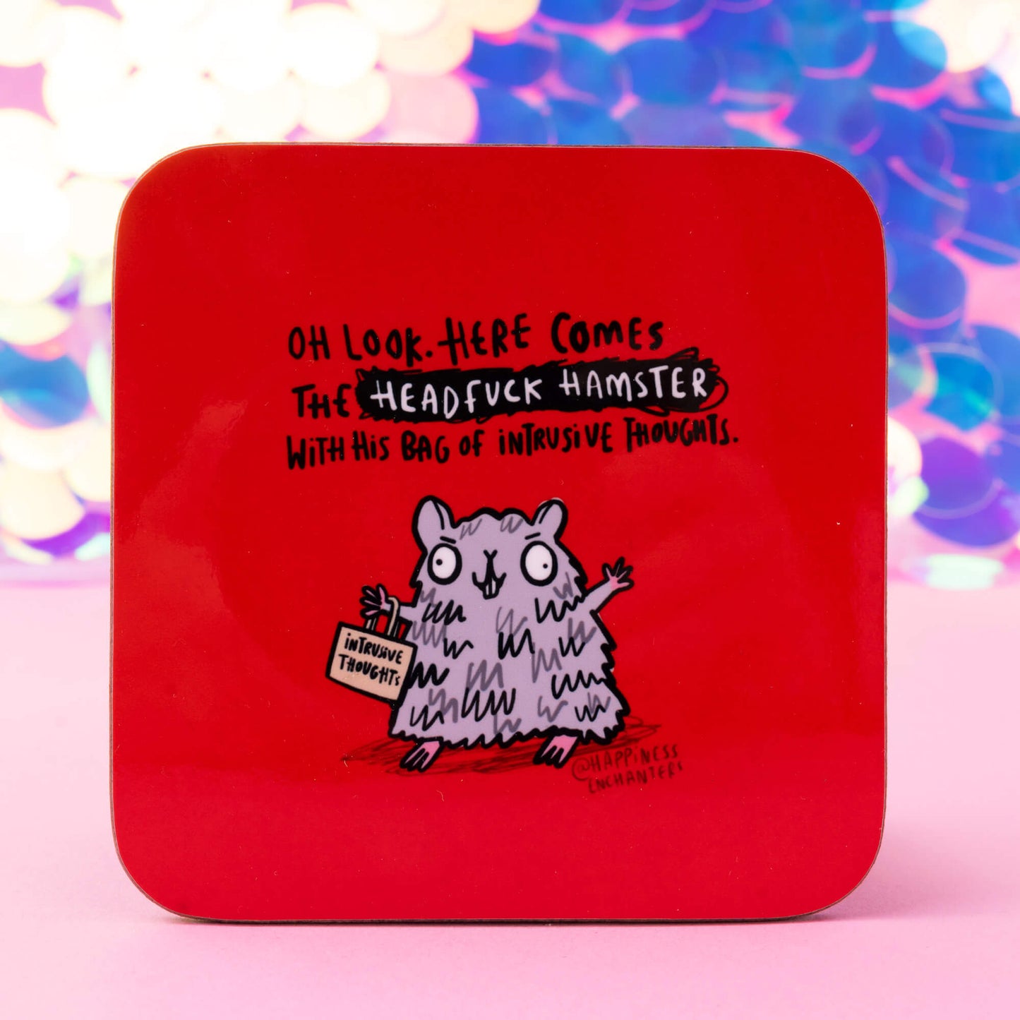 Red coaster by Happiness Enchanters featuring a humorous illustration of a grey hamster holding a sign that reads 'Intrusive Thoughts.' The text above reads: 'Oh look, here comes the Headfuck Hamster with his bag of intrusive thoughts.' A whimsical product combining humour and mindfulness.