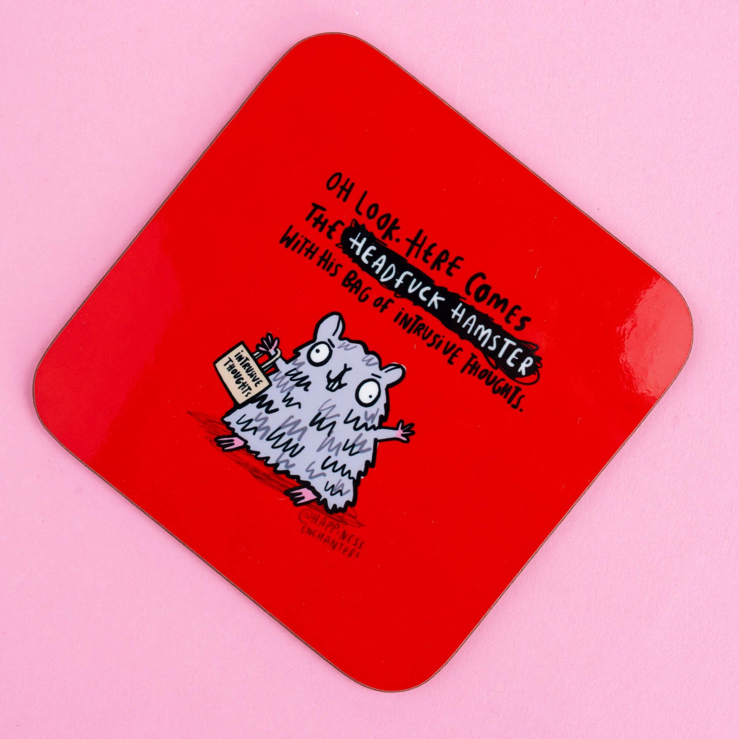 Close-up of a quirky red coaster from Happiness Enchanters, showcasing a cartoon hamster labelled 'Headfuck Hamster' with a sign reading 'Intrusive Thoughts,' blending comedy with a nod to mental health awareness.