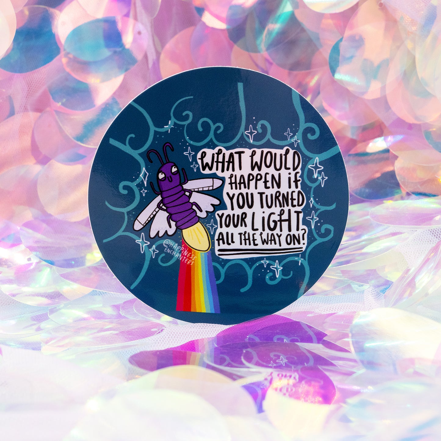 A round vinyl sticker by Happiness Enchanters featuring a cute purple firefly with glowing yellow light trailing a rainbow beam. Surrounded by teal swirls and stars, the text reads “What would happen if you turned your light all the way on?”. Set against a dreamy iridescent background. Magical positive affirmation sticker by Katie Abey and Angela Sandland.