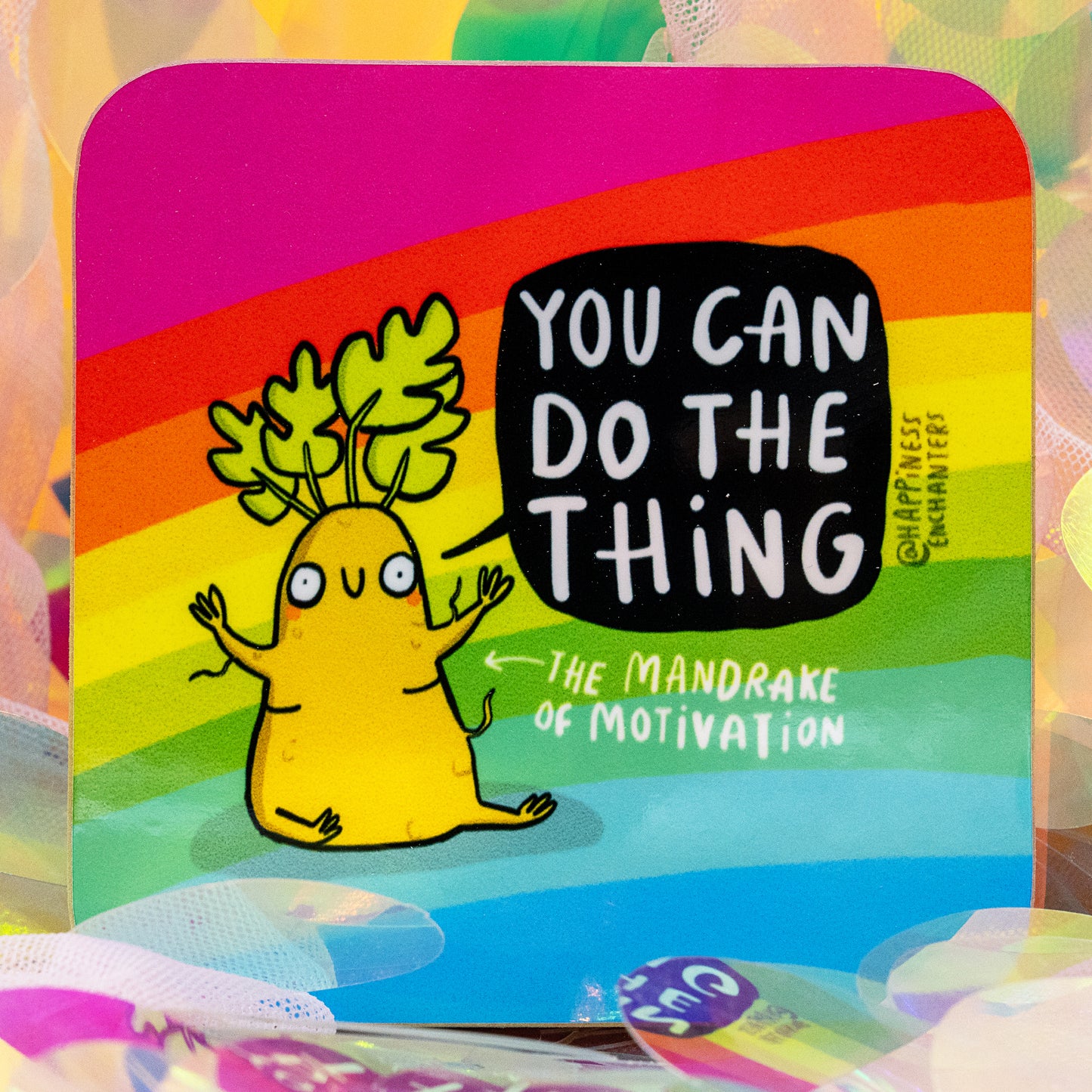 A colourful square coaster by Happiness Enchanters featuring a rainbow background and a cute illustrated mandrake character with leafy hair. The coaster reads “You Can Do The Thing – The Mandrake of Motivation.” Designed by Katie Abey and Angela Sandland, this magical artwork inspires encouragement and positivity.