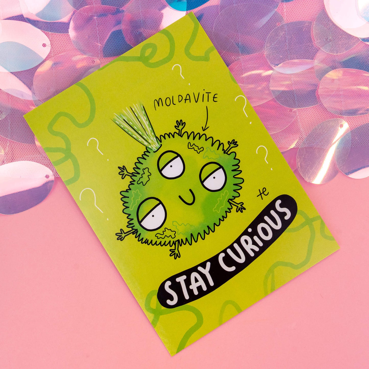 A whimsical Moldavite-themed postcard from 'Happiness Enchanters', featuring a cute, cartoon Moldavite crystal character with three eyes and spiky hair, accompanied by the text 'Stay Curious' on a vibrant green background with swirling patterns and question marks. The postcard exudes a magical and playful vibe.