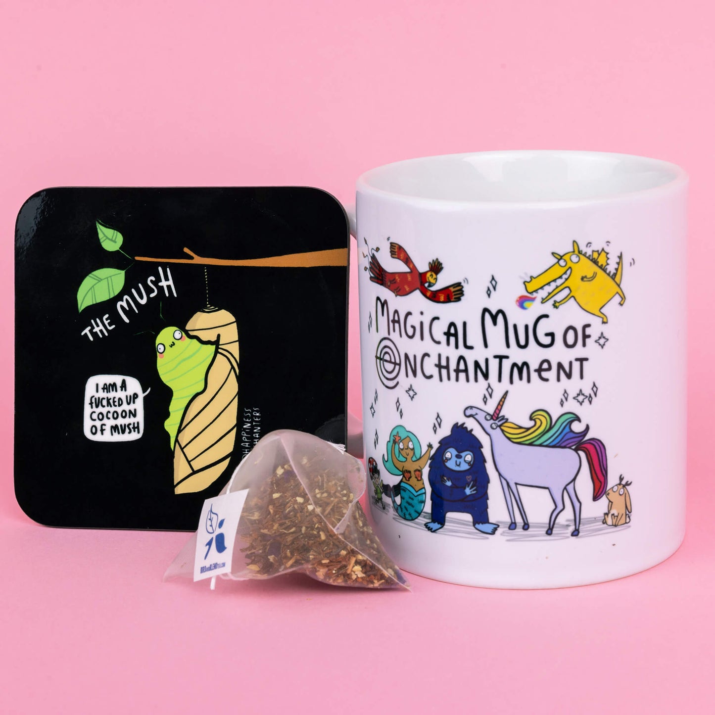 The Happiness Enchanters Cocoon of Mush coaster sat next to the Magical Mug of Enchantment on a pastel pink background with a tea bag