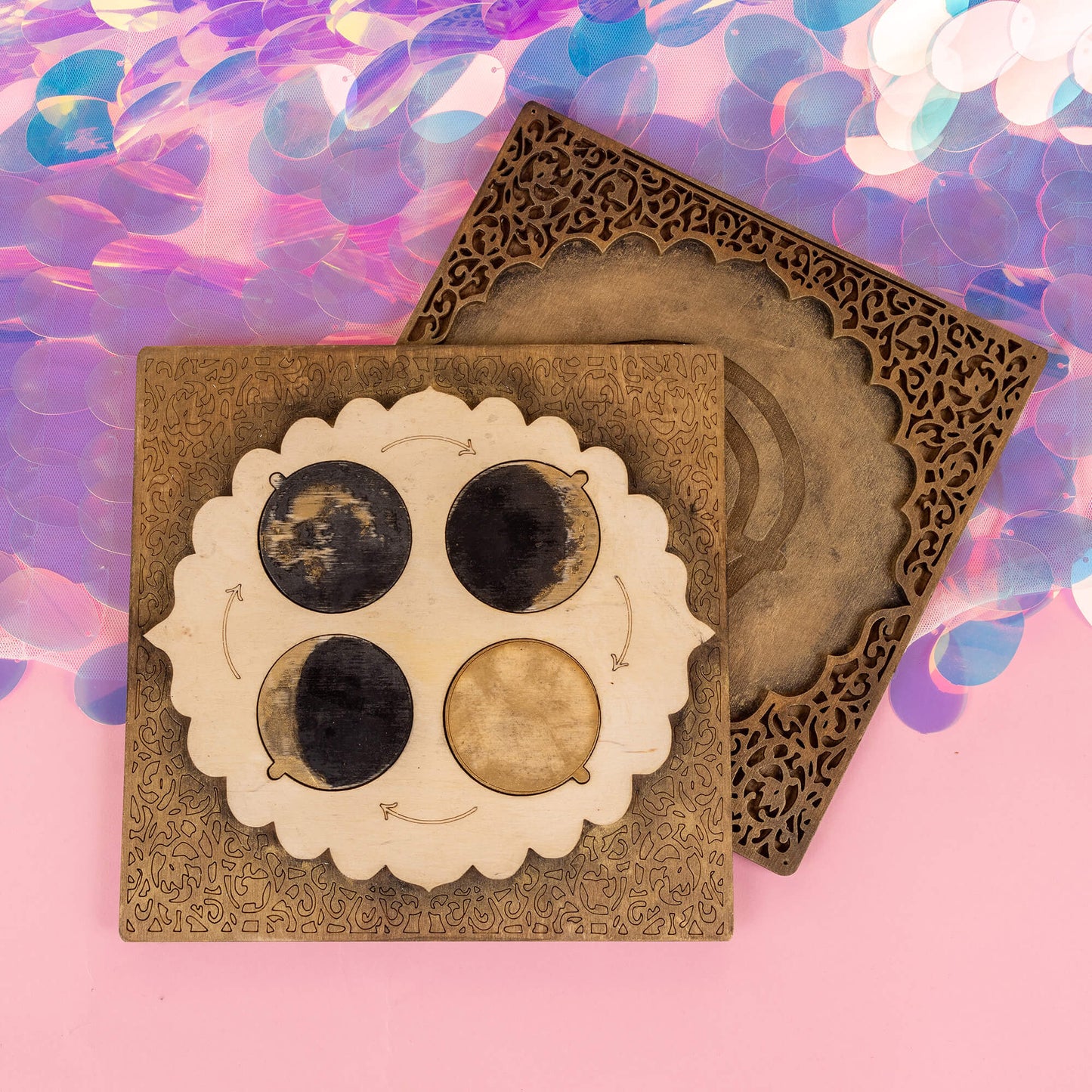 The power portal by Happiness Enchanters, engraved with lunar phases—new moon, waxing moon, full moon, and waning moon—designed to align with natural rhythms. The bronze and wood tones contrast beautifully with a shimmering, holographic background.