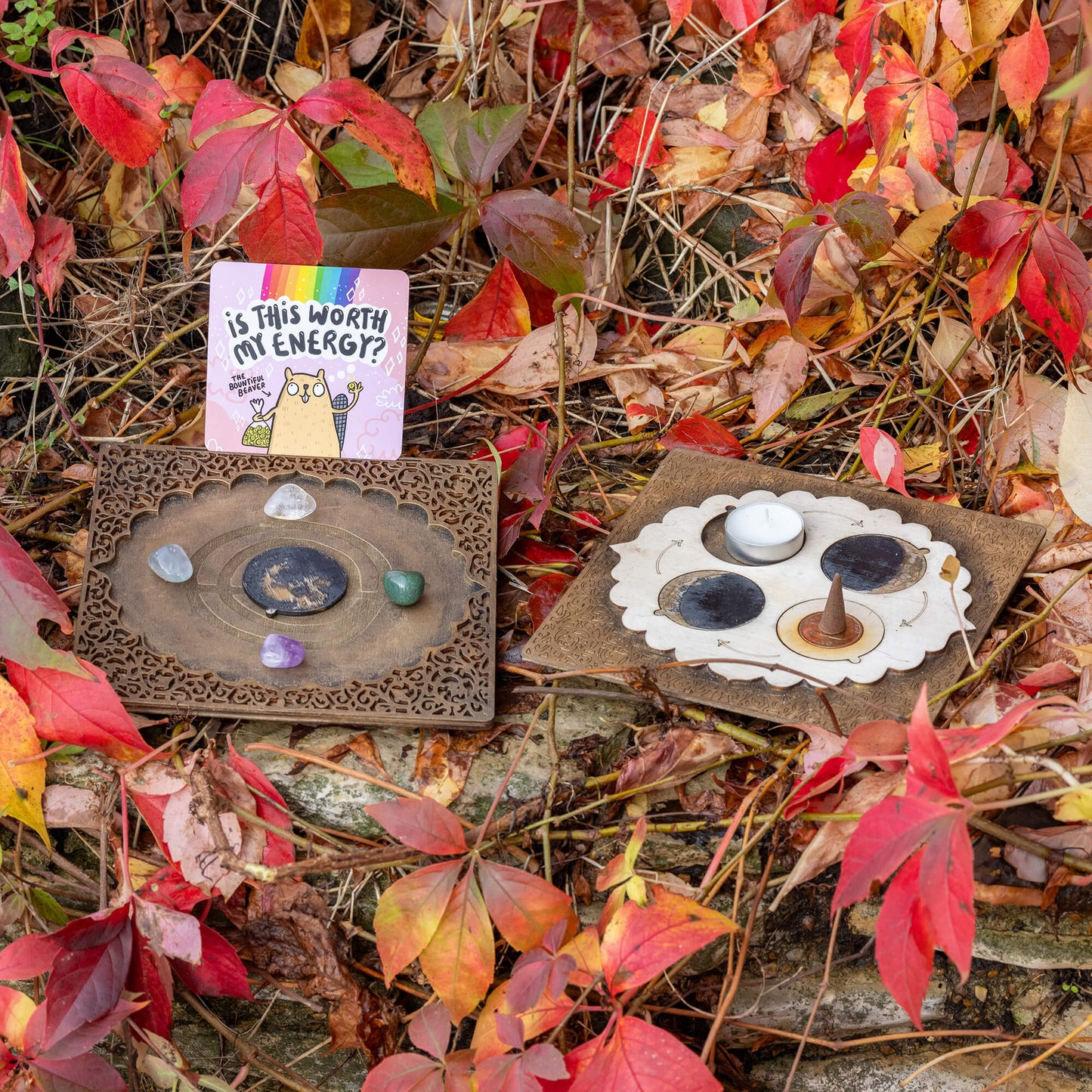 A serene outdoor setup featuring the Power Portal Board by Happiness Enchanters, placed among fallen autumn leaves. Crystals, candles, and incense are arranged in harmony with nature, creating a perfect space for reflection and magical rituals.