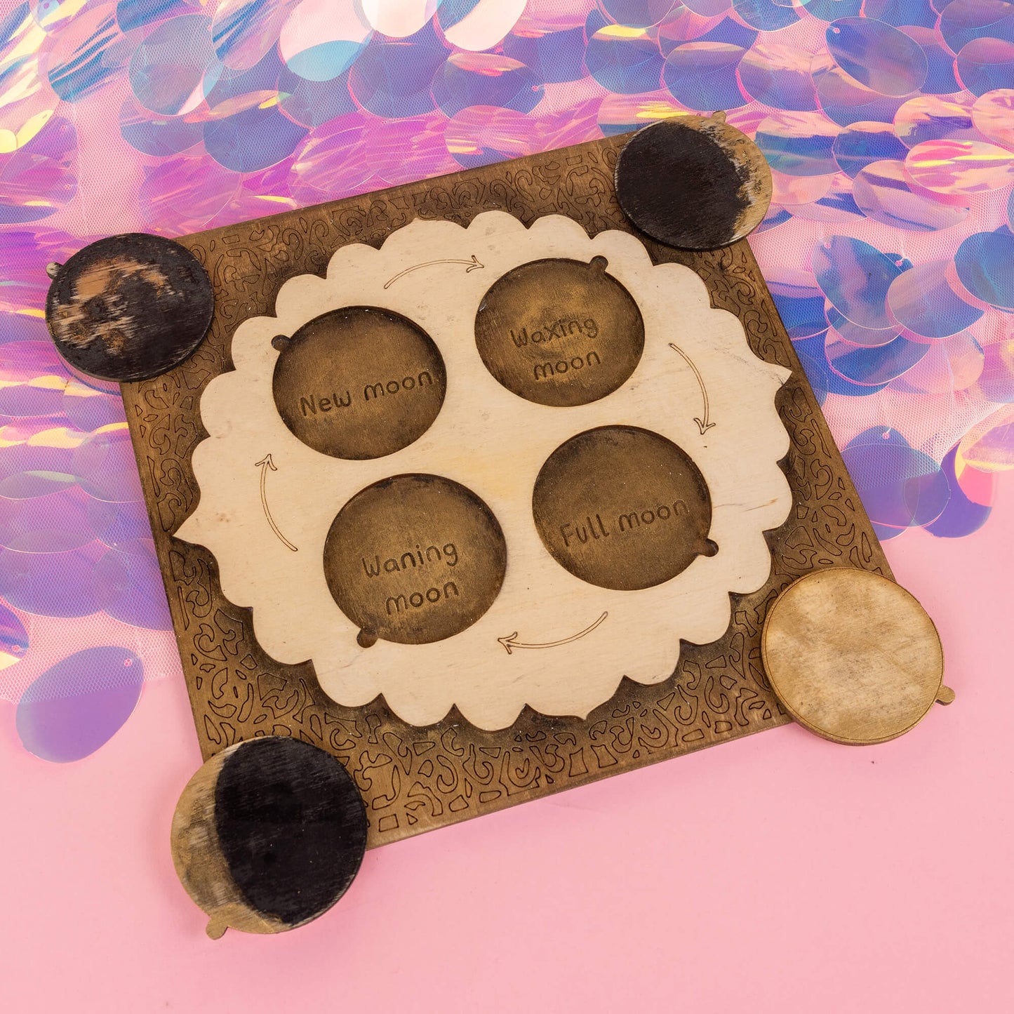 The power portal by Happiness Enchanters, engraved with lunar phases—new moon, waxing moon, full moon, and waning moon—designed to align with natural rhythms. The bronze and wood tones contrast beautifully with a shimmering, holographic background.