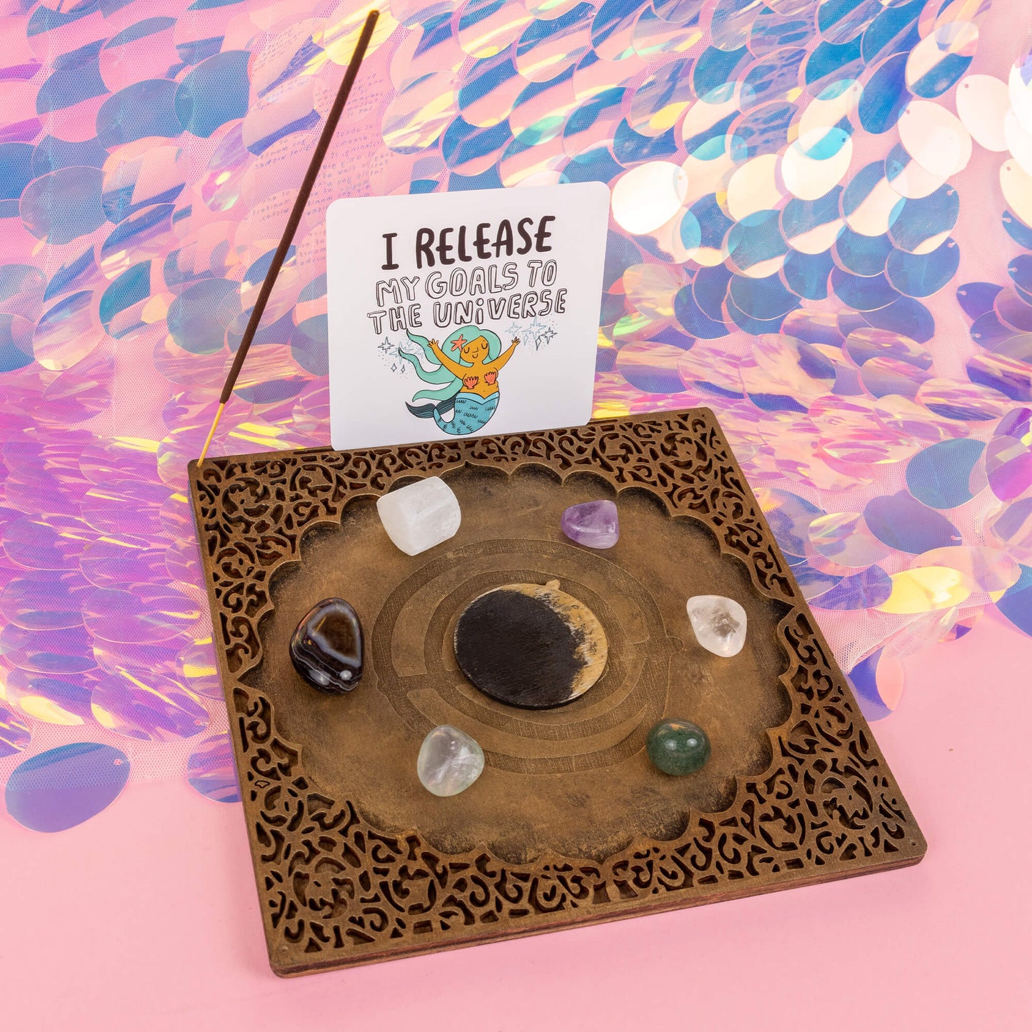 The Power Portal by Happiness Enchanters is adorned with crystals, including amethyst, clear quartz, and aventurine. An oracle card in the portal reads, "I release my goals to the universe". An incense stick is also placed in the portal