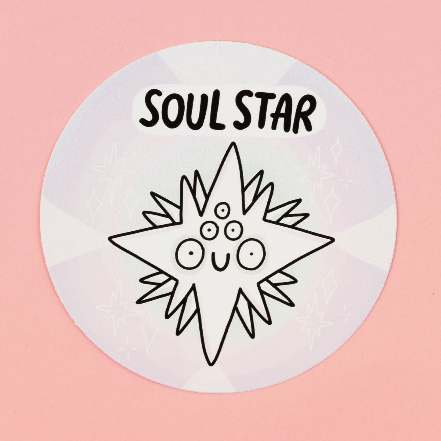Soul star Chakreatures sticker by Happiness Enchanters. A circular sticker with a white diamond shaped creature illustrated by Katie Abey with multiple eyes and smiling mouth on a white background. 'Soul Star' is written above the character. The sticker is sat on a pink backdrop.