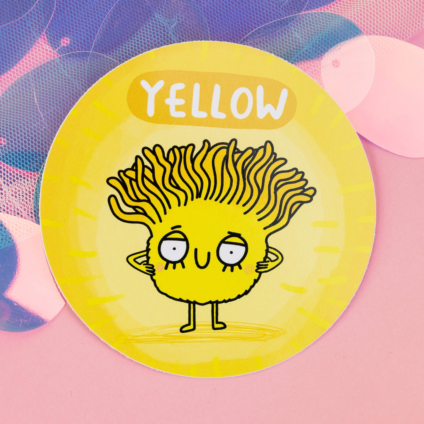 Yellow Chakreatures sticker by Happiness Enchanters. A circular yellow sticker with cute cartoon yellow creature with flowing hair illustrated by Katie Abey. 'Yellow' is written above the character. The sticker is on a pink backdrop.