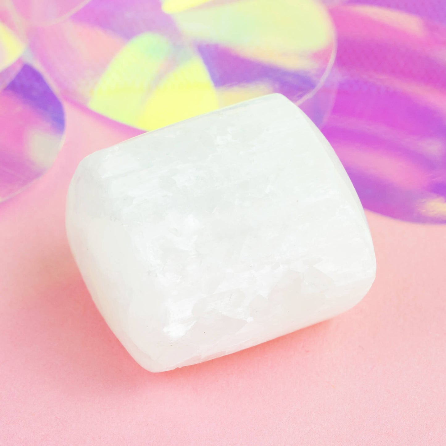 Happiness Enchanters selenite crystal on a pink holographic backdrop