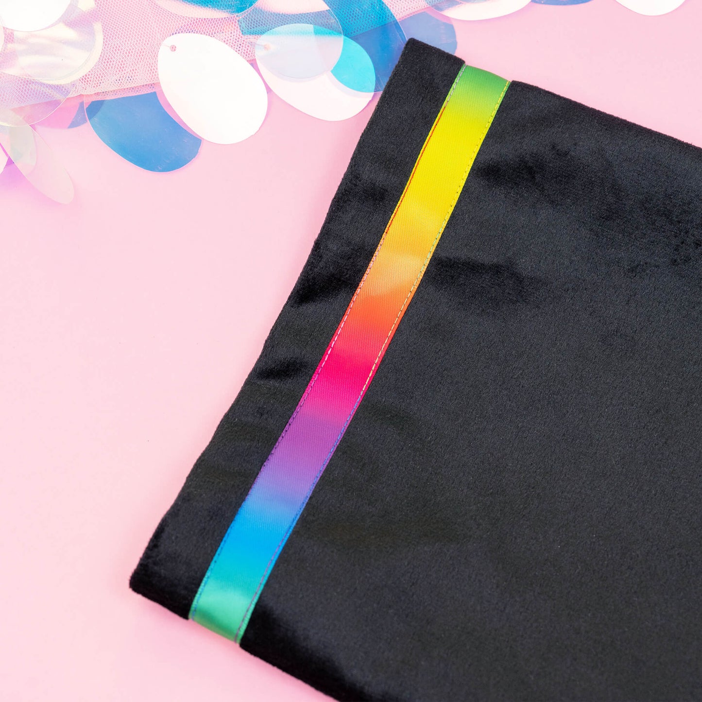 Close-up of Happiness Enchanters black velvet bag with a striking rainbow trim, highlighting the fine craftsmanship and luxurious texture, set against a pink background. Perfect for embodying the brand’s mystical and creative essence.