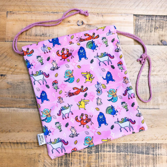 happy enchanted oracle bag in pink with lots of cute Katie Abey illustrations on a wooden table