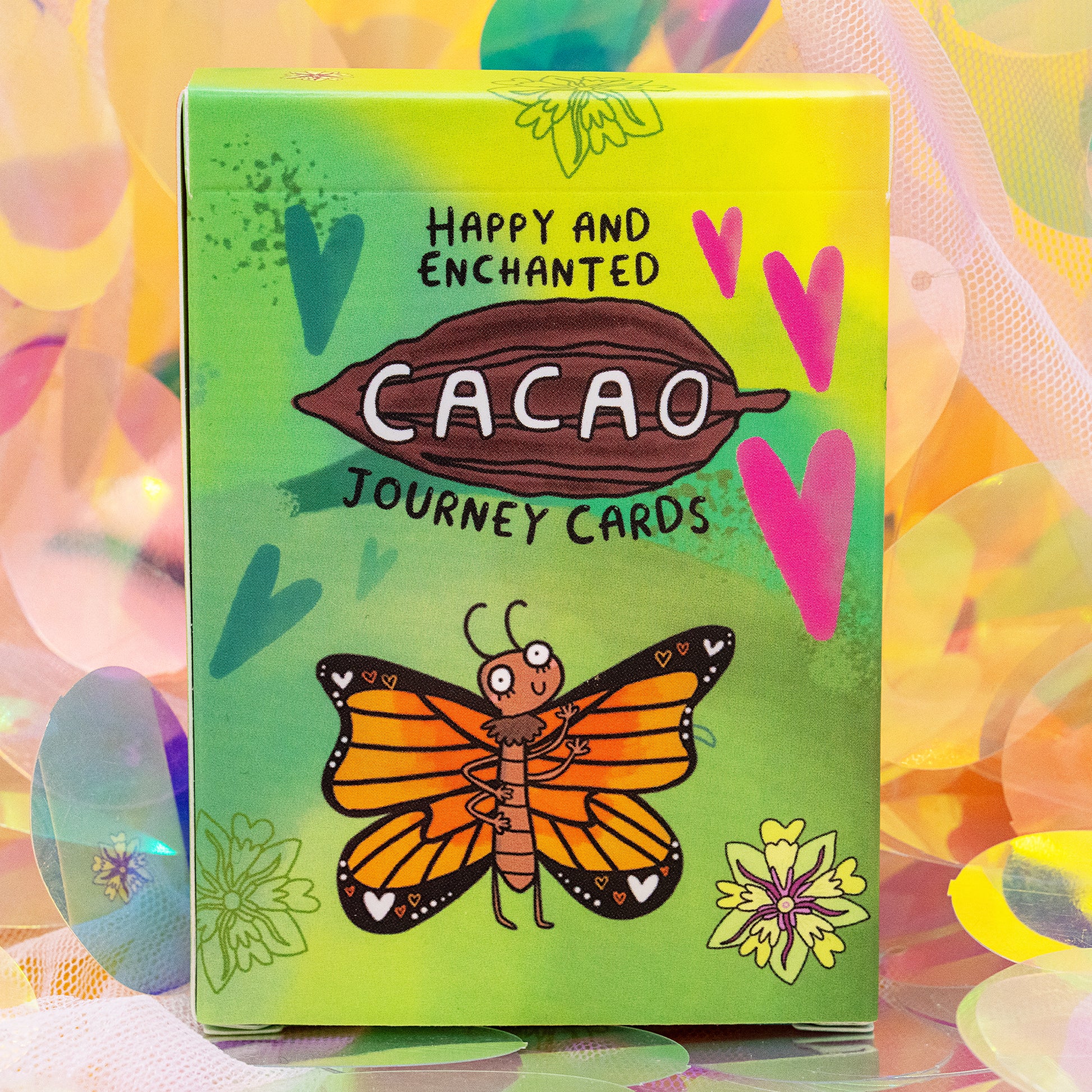 Front of the Cacao Journey Cards box by Happiness Enchanters, featuring a bold cacao pod illustration, hearts and a butterfly. Designed by Katie Abey and Angela Sandland for cacao rituals, mindfulness and plant spirit connection.