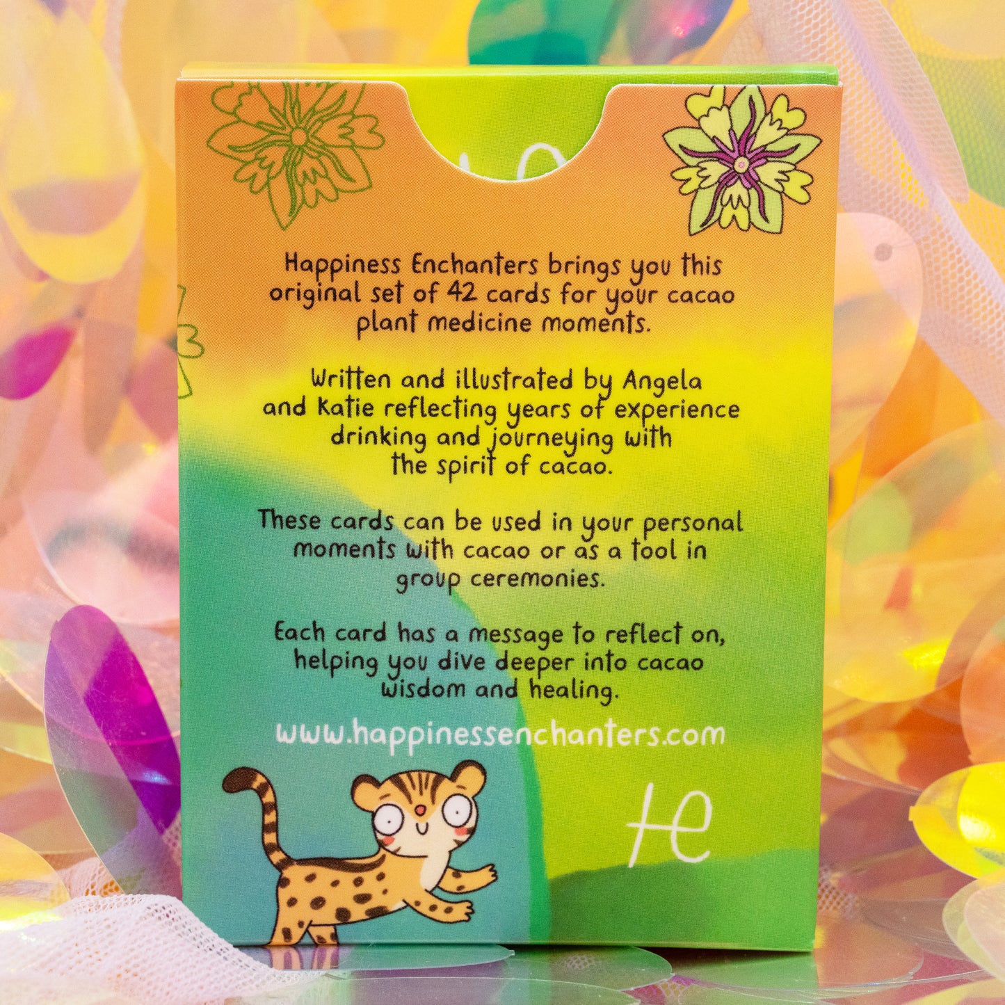 Back of the Cacao Journey Cards box by Happiness Enchanters with rainbow gradient colours and illustrated leopard. Text introduces the 42 card deck by Katie Abey and Angela Sandland for cacao ceremonies, meditation and spiritual reflection.
