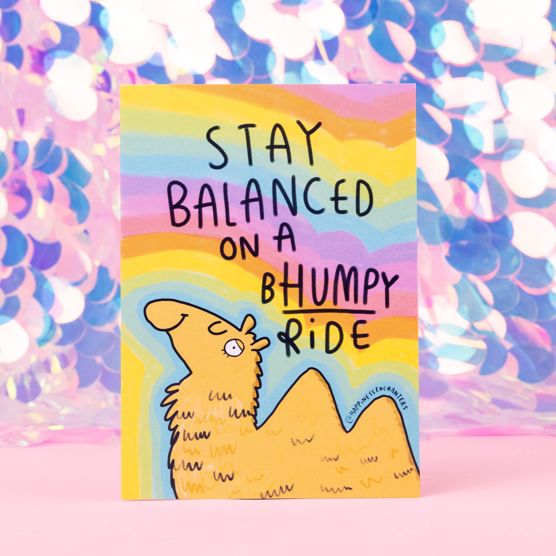 a drawing by Katie Abey of a camel with stay balanced on a bumpy ride with a rainbow swirly background