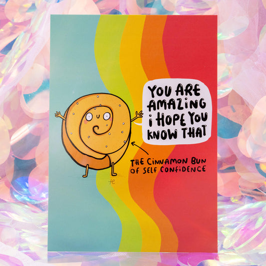 The Cinnamon Bun of Self Confidence postcard by Happiness Enchanters featuring a smiling cinnamon bun illustration by Katie Abey with the message “You are amazing I hope you know that,” on a vibrant rainbow background with soft pastel iridescent backdrop.