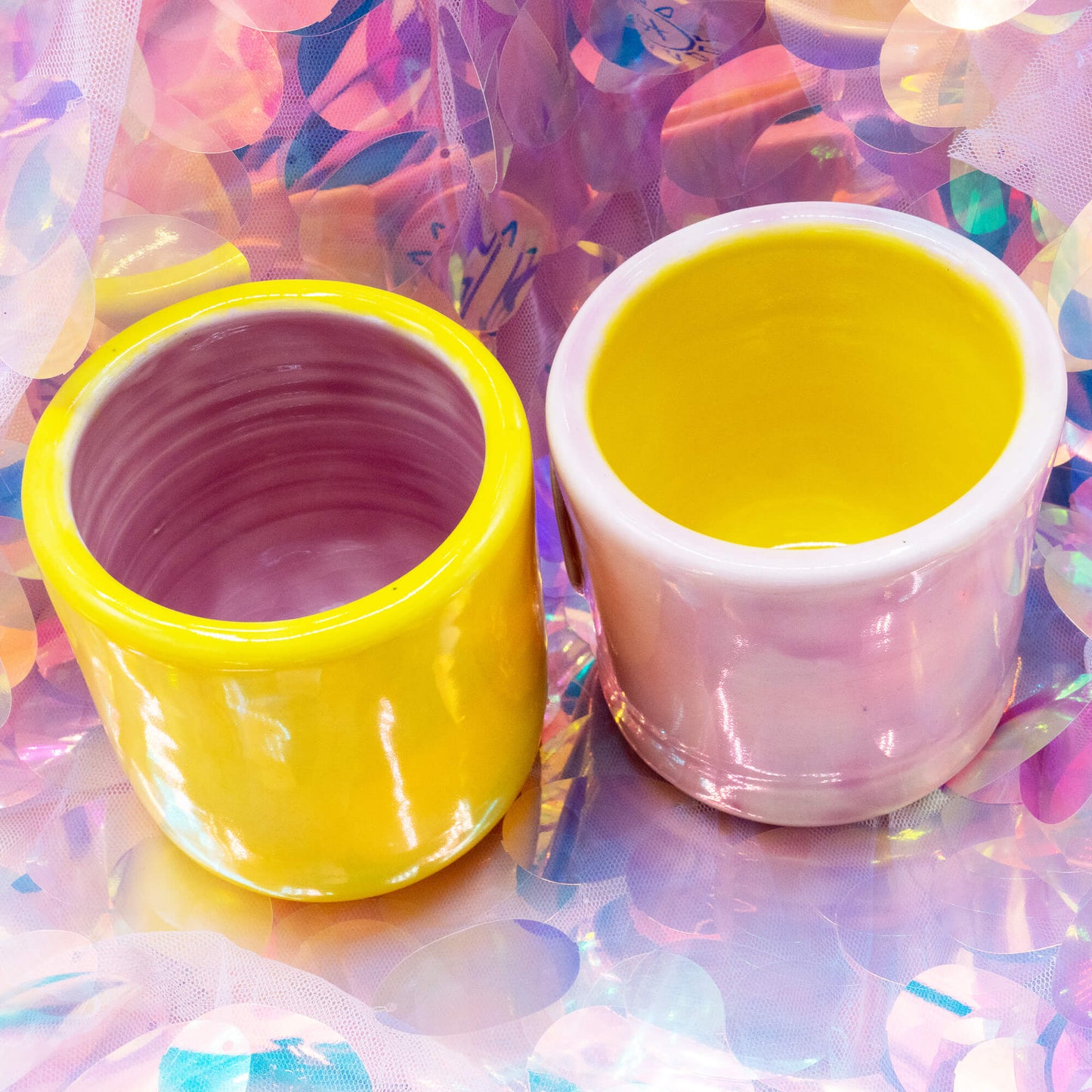 Angled view of yellow and pink Happiness Enchanters cacao cups showing glossy finish and colour contrast.