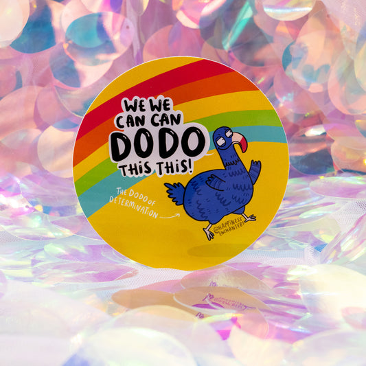 A round rainbow sticker reading “We Can Dodo This!” by Happiness Enchanters, created by Katie Abey & Angela Sandland. Features a cute blue dodo labelled “The Dodo of Determination”. Shot against an iridescent pastel background. Motivational vinyl sticker for planners, journals, scrapbooks, and gifts.