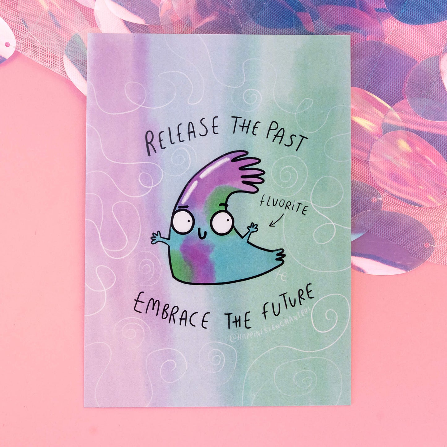 A whimsical Fluorite-themed postcard from 'Happiness Enchanters', featuring a cute, cartoon Fluorite crystal character with the text 'Release the past, embrace the future' on a pastel, swirly-patterned background. The postcard exudes a magical and playful vibe.