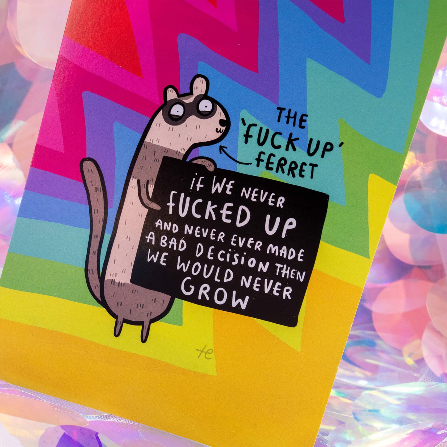 Close-up of The ‘Fuck Up’ Ferret Postcard by Happiness Enchanters, illustrated by Katie Abey. The rainbow postcard features a cute ferret holding a sign that says “If we never fucked up and never ever made a bad decision then we would never grow.” Surrounded by colourful zigzags and a whimsical, uplifting vibe.
