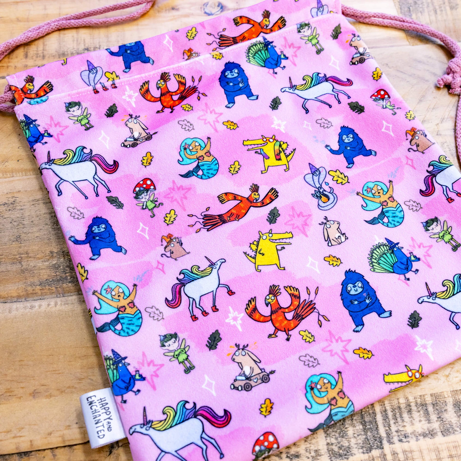 happy enchanted oracle bag in pink with lots of cute Katie Abey illustrations on a wooden table