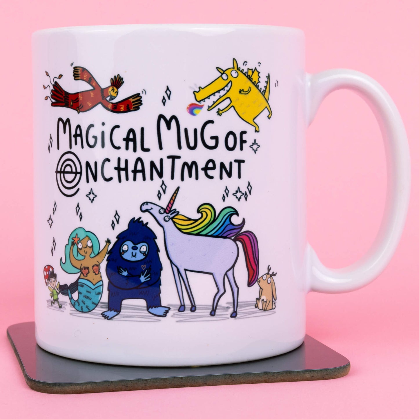 A white mug featuring whimsical characters designed by Katie Abey, including a vibrant rainbow unicorn, a blue creature, a mermaid, and a cheerful bird. Text reads "Magical Mug of Enchantment," surrounded by magical sparkles, against a pink background. Created by Happiness Enchanters, blending art and enchantment.