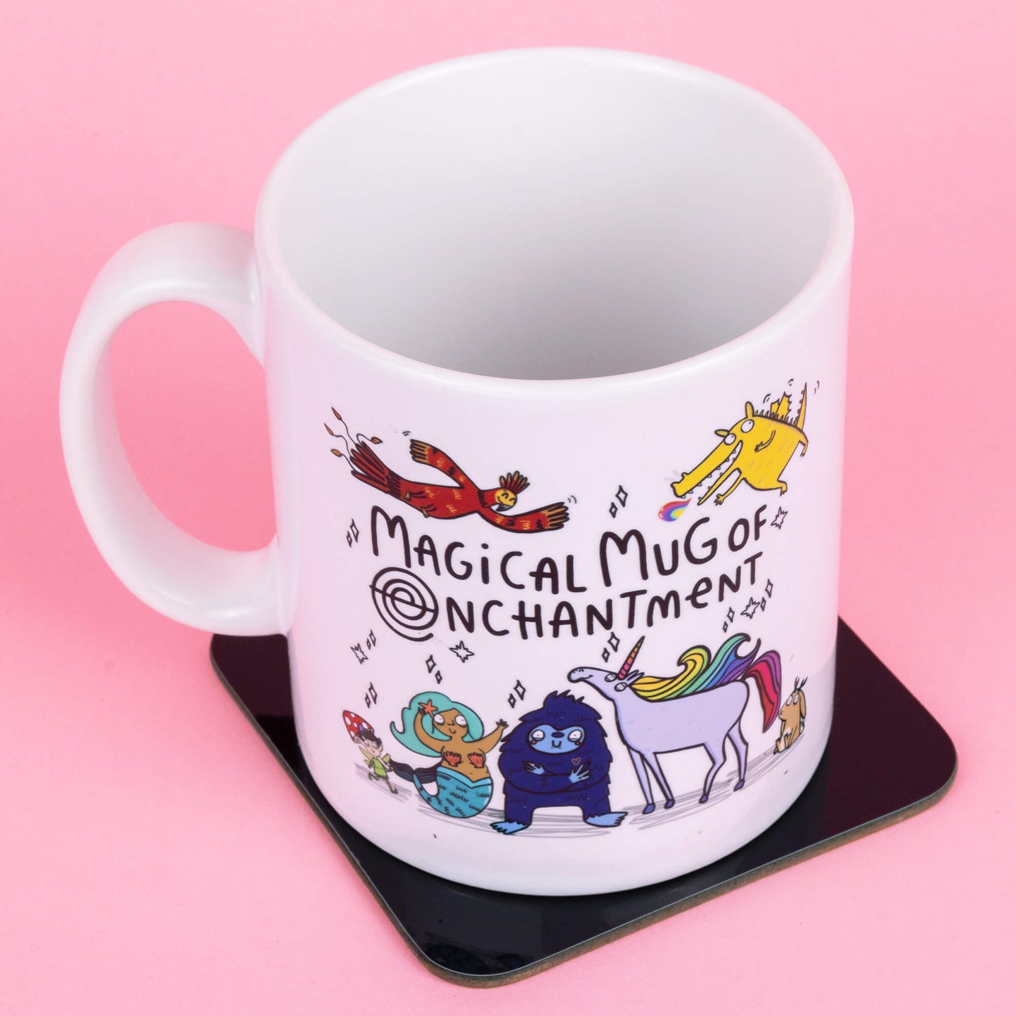 A white mug featuring whimsical characters designed by Katie Abey, including a vibrant rainbow unicorn, a blue creature, a mermaid, and a cheerful bird. Text reads "Magical Mug of Enchantment," surrounded by magical sparkles, against a pink background. Created by Happiness Enchanters, blending art and enchantment.