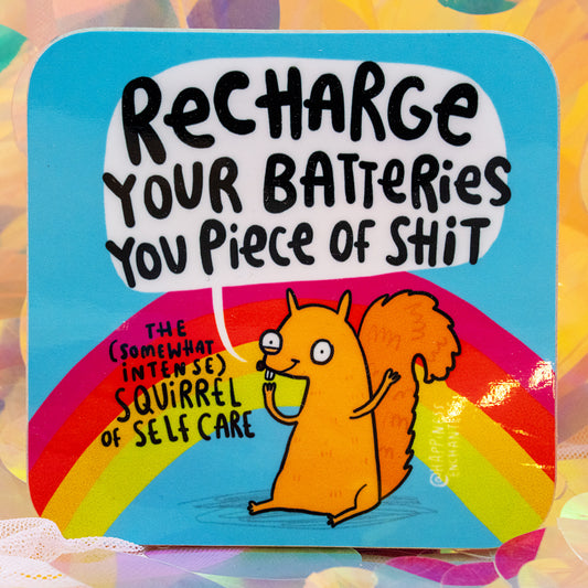 Close-up of the Happiness Enchanters “Somewhat Intense Squirrel of Self Care” coaster by Katie Abey and Angela Sandland. The bright rainbow design shows a cute orange squirrel with the phrase “Recharge Your Batteries You Piece of Shit”. Photographed against shimmering pastel sequins. Colourful, sweary self care coaster.