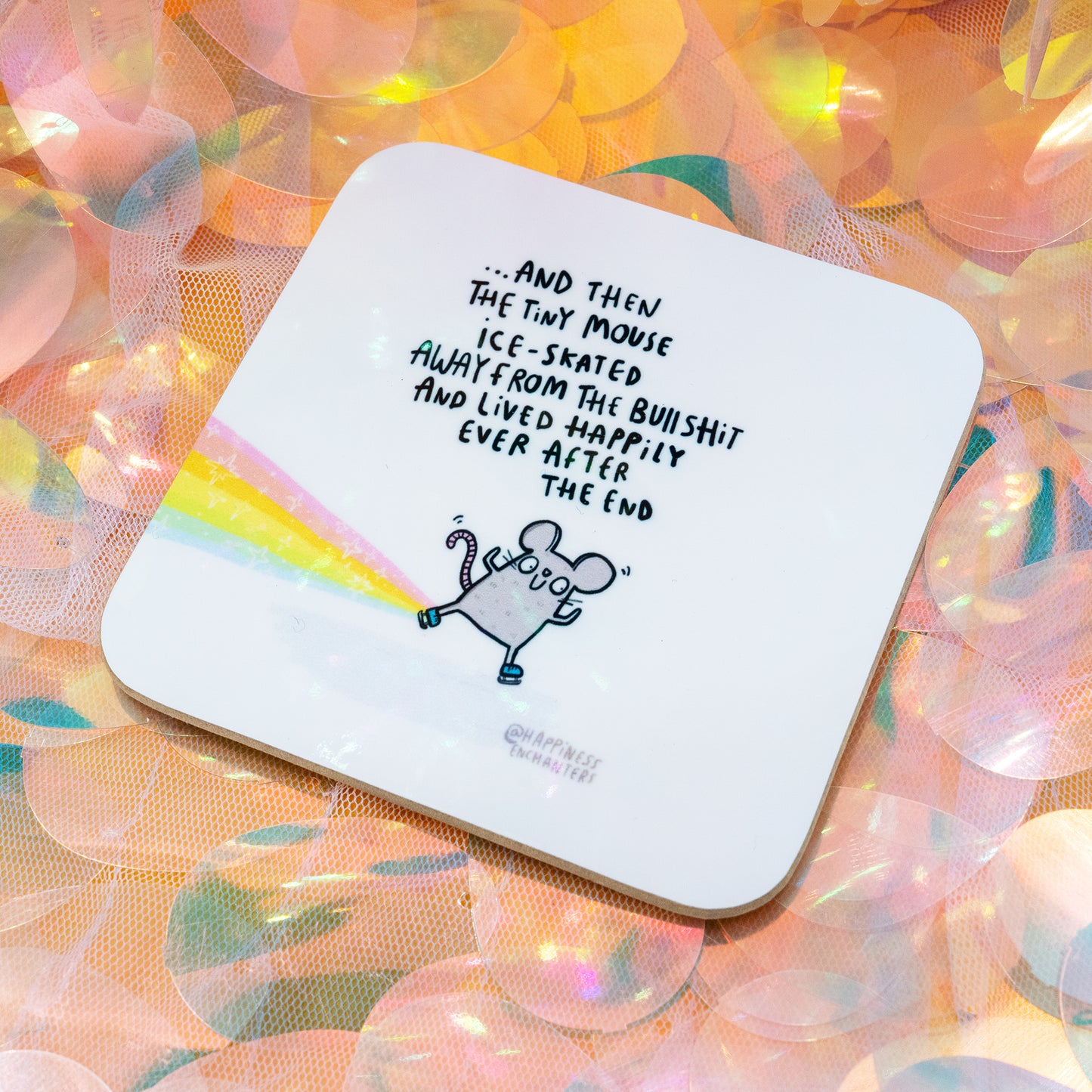 Happily Ever After Tiny Mouse Coaster by Happiness Enchanters, featuring a cute illustrated mouse ice-skating away on a rainbow trail with the quote “And then the tiny mouse ice-skated away from the bullshit and lived happily ever after. The end.” Coaster displayed on a pastel iridescent background. Designed by Katie Abey and Angela Sandland.
