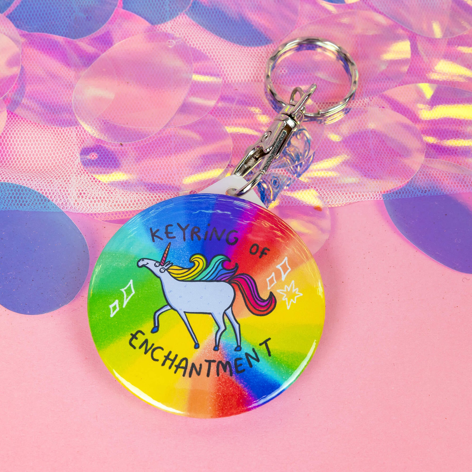 A keyring with a unicorn illustration on a rainbow base with sparkles and the keyring of enchantment in text