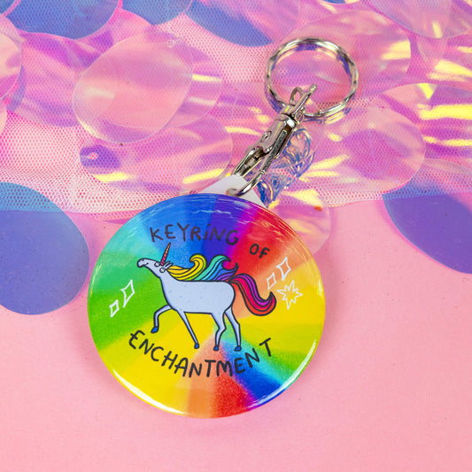 A keyring with a unicorn illustration on a rainbow base with sparkles and the keyring of enchantment in text