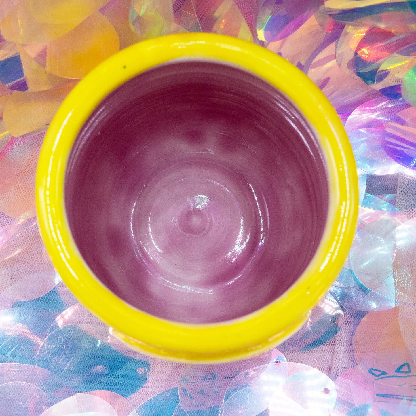 Overhead view of the yellow Happiness Enchanters handmade ceramic cup showing pink glazed interior.