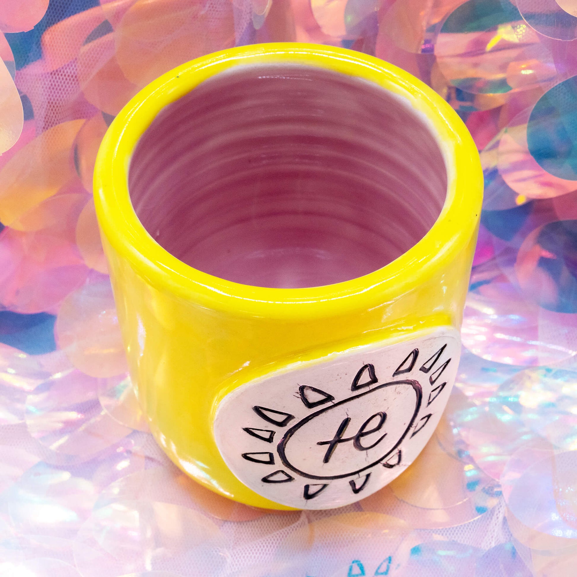 Close-up of the Happiness Enchanters handmade yellow ceramic cacao cup showing the carved sun and symbol design detail.